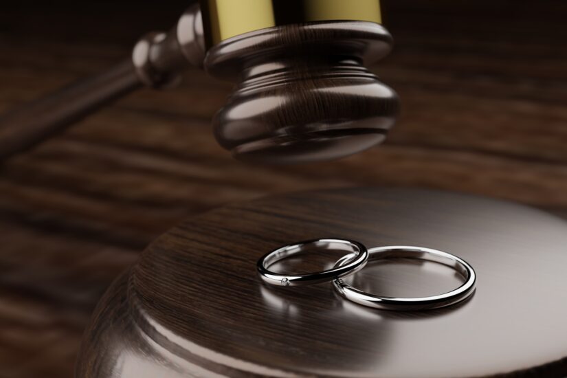 Judges Hammer Hitting Two Engagement Rings Laying On A Table